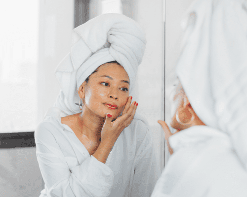 Close up of woman looking in the mirror touching her face