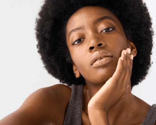 Close up of a woman with clear skin and her hand on her face