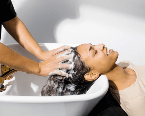 A woman getting her hair washed in a salon sink