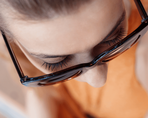 Close up from above a woman's sunglasses to show her long, full lashes