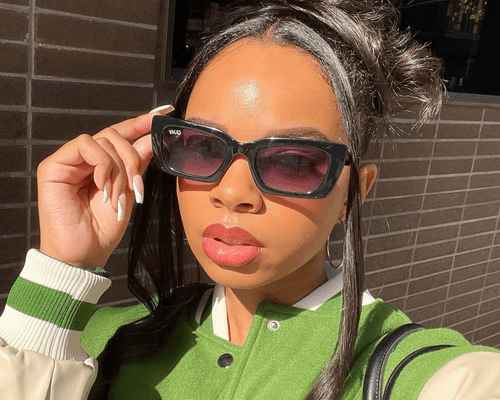 A close-up of a woman wearing sunglassesÂ and an updo with glossy, full, pink lips.Â 