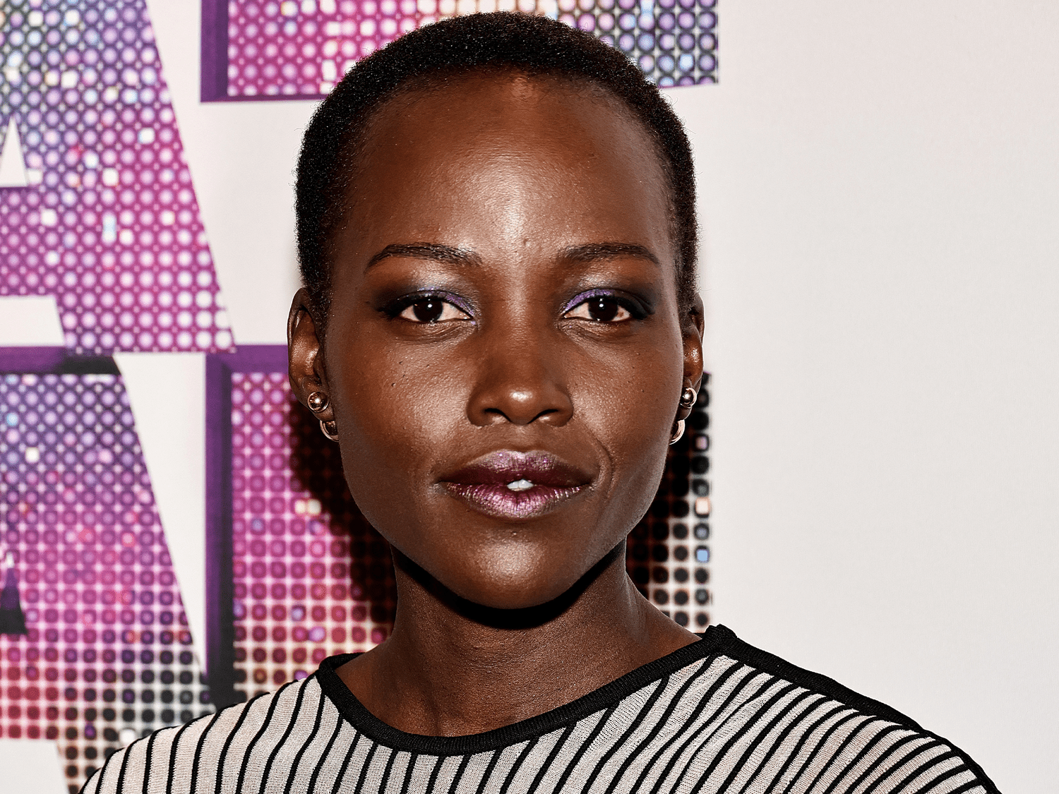 Lupita Nyong'o wearing purple eyeshadow and frosted lips