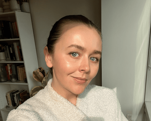 woman with rosy cheeks standing near window