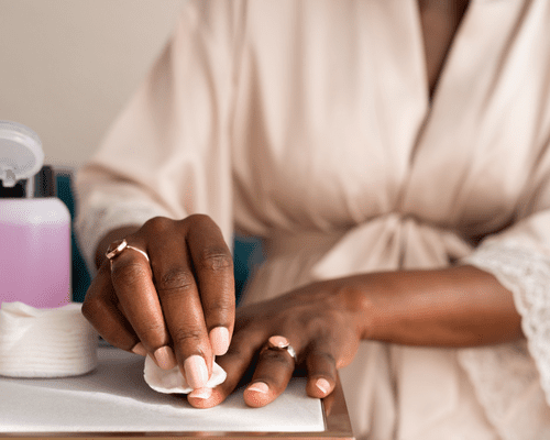 Hands with a cotton round and nail polish remover