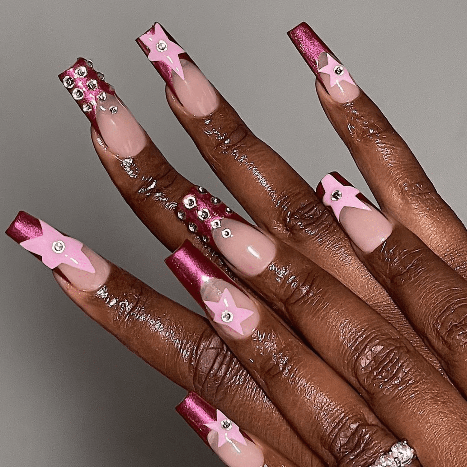 Manicure with metallic pink French tips and light pink star adorned with rhinestones 