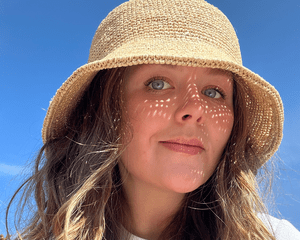 byrdie editor holly rhue wearing woven sun hat 