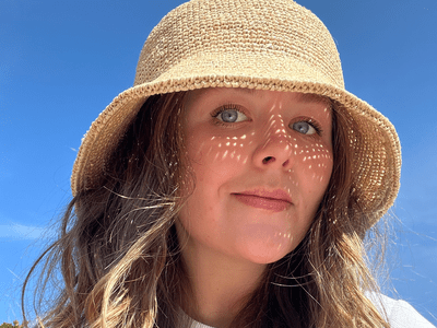 byrdie editor holly rhue wearing woven sun hat 