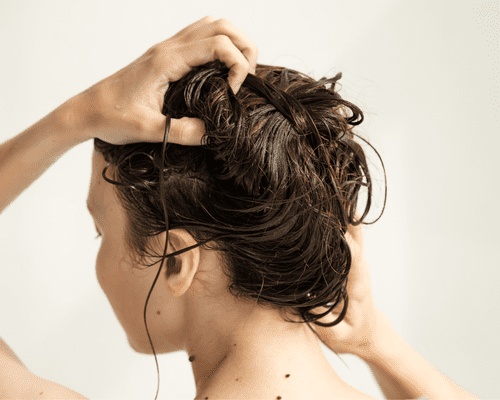 A woman washing her hair and scrubbing her scalp