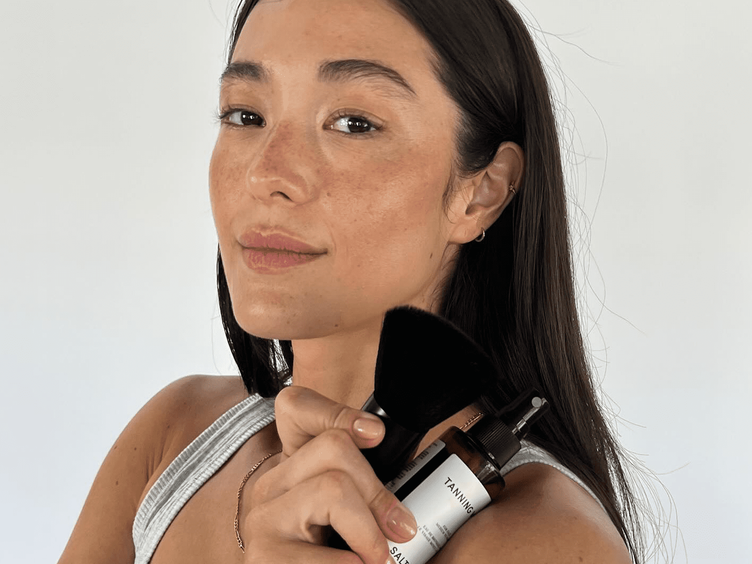 woman with self tanner on face on white background