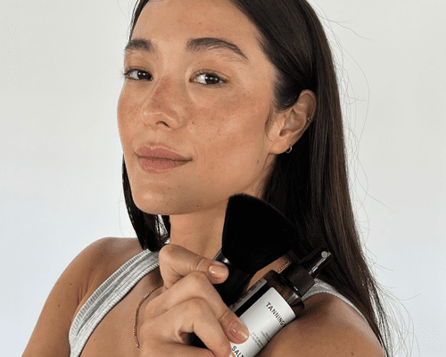 woman with self tanner on face on white background