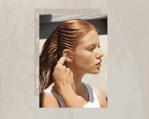 woman with red hair combing stands behind ear