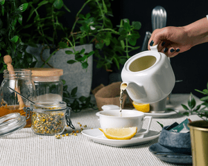 A hand holding a teapot and pouring tea into a cup