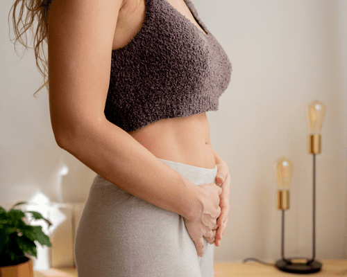 Close up of a woman standing with her hands on her abdomen