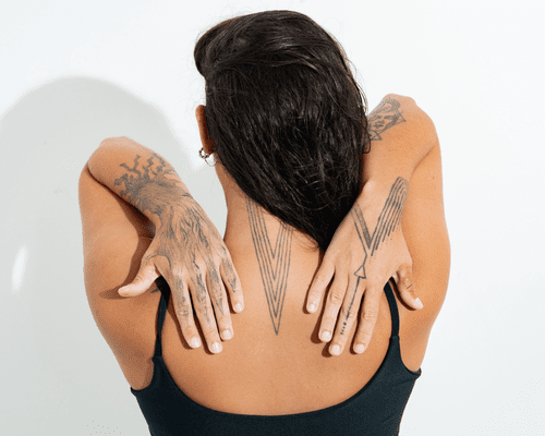 Close up of a models back and forearms with detailed nature tattoos.