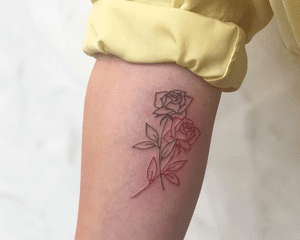 A close up of a forearm with a two-tone rose tattoo.