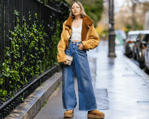 Model wearing a tan sherpa jacket, lightwash wide-leg jeans, and chestnut platform ugg boots.