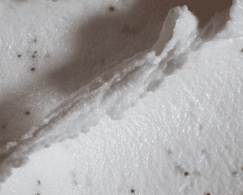 Close up of white haircare product, with pink beads. 