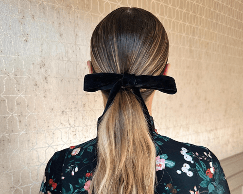 Close up of the back of a woman's head with hair in a ponytail and a bow