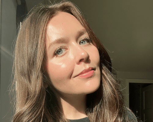 woman in 20s with glowy skin smiling at camera